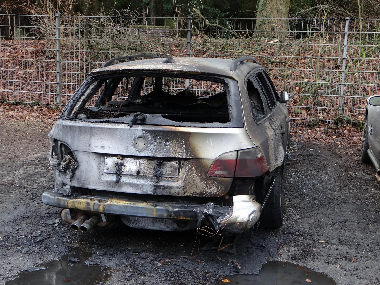 Rear view of a burnt car wreck outdoors, damaged and charred.